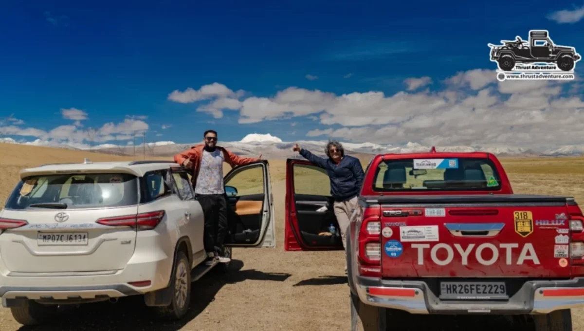 A red Toyota Hilux and a white Fortuner on the road of Tibet.